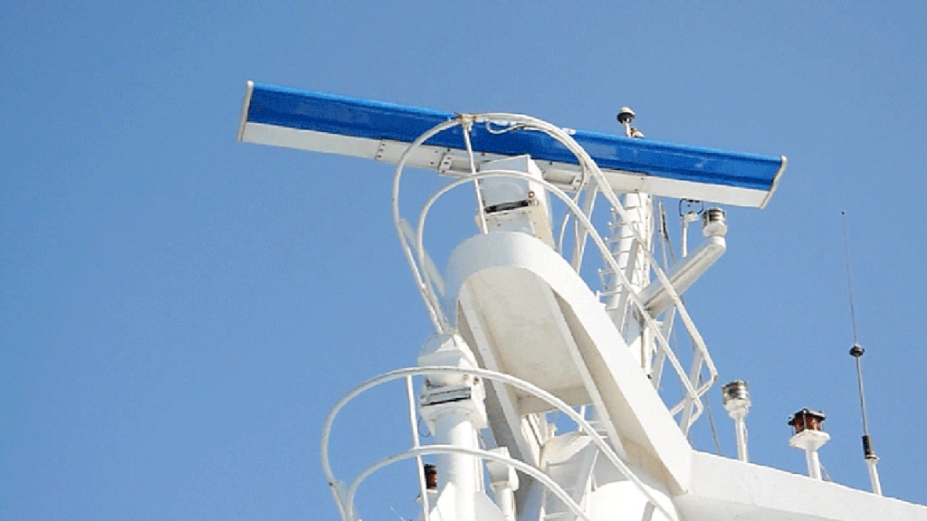 Rotating marine radar on white boat against blue sky